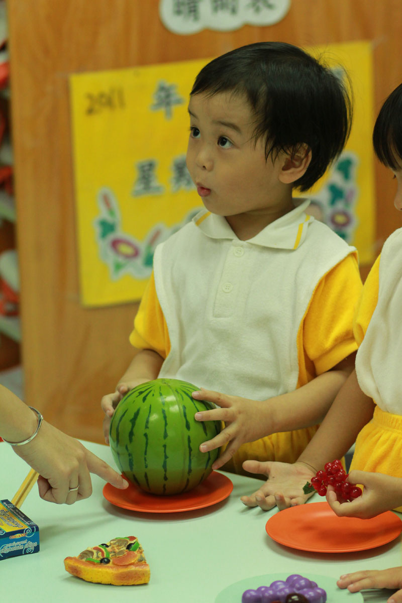 A child is holding a small water melon
