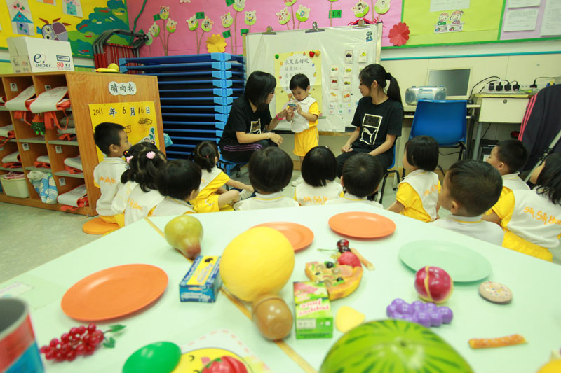 A teacher is teaching the children to sing the song "Delicious fruits"