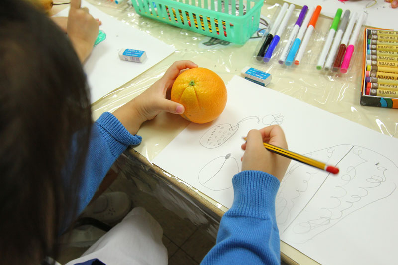 A child is drawing an orange