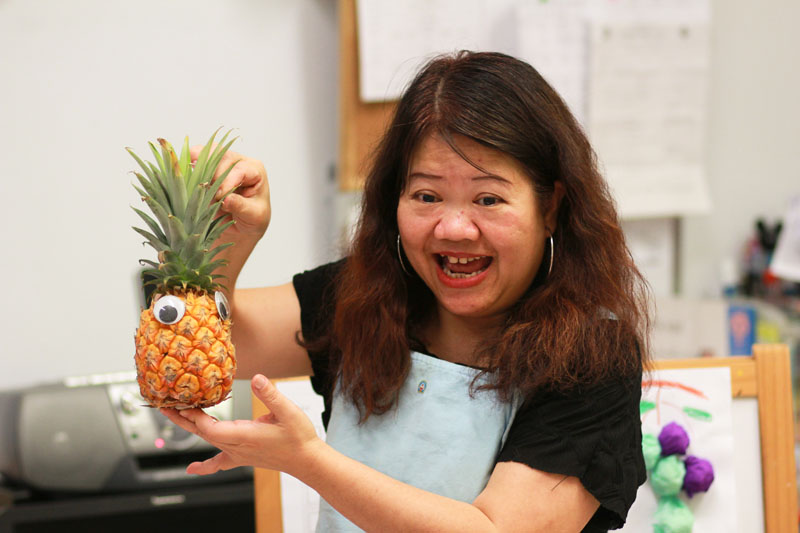 A teacher is using a pineapple as her props