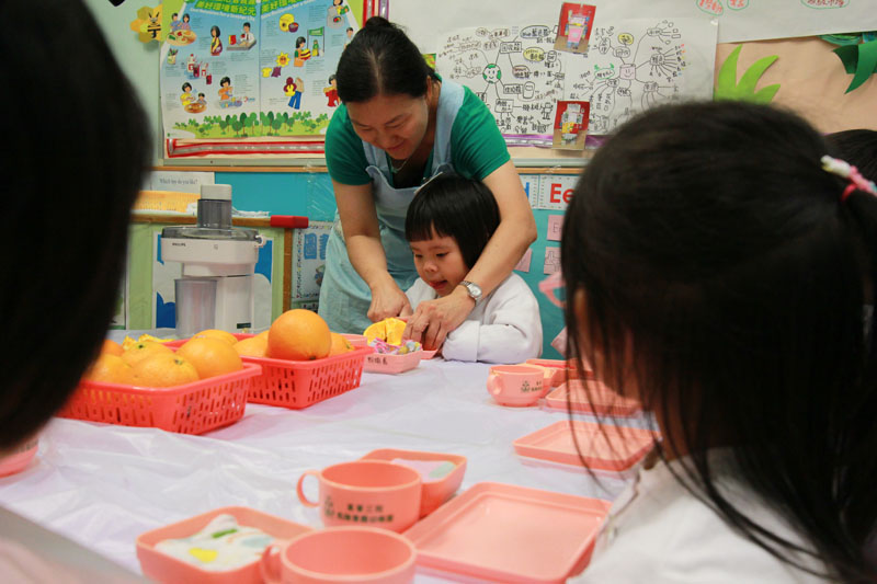 Teacher and children are cutting fruit together