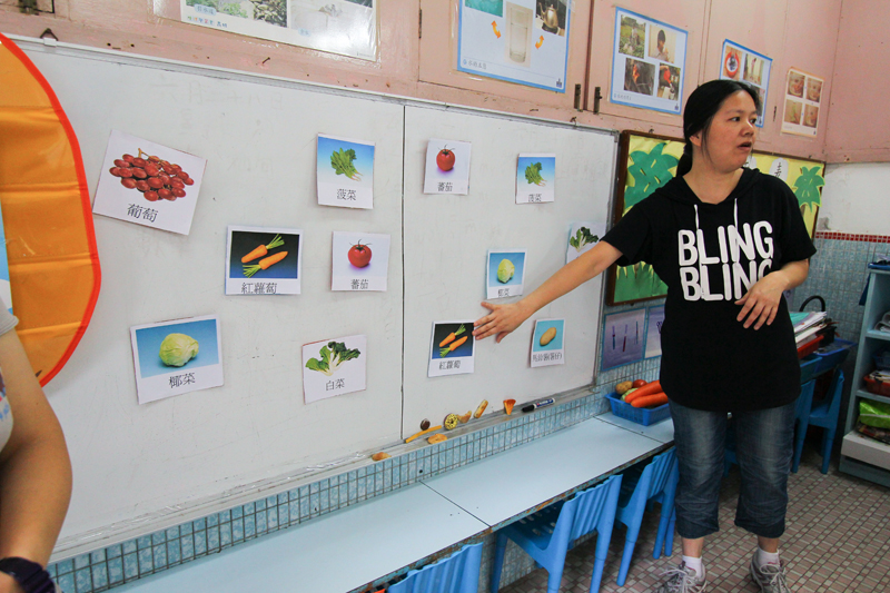 A teacher is teaching the names of different vegetables