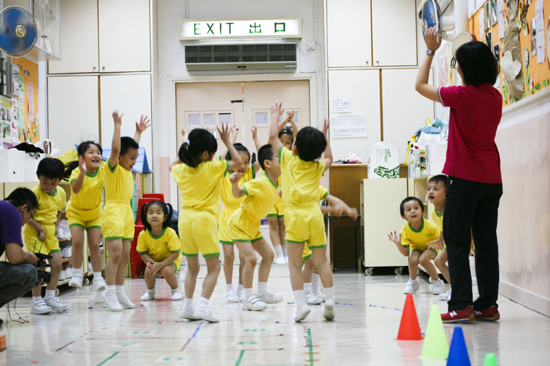 A teacher is teaching the children to do physical activity