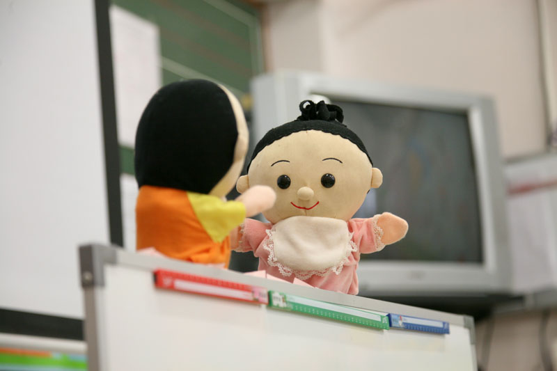 A teacher is using a puppet to tell children the importance of drinking water regularly
