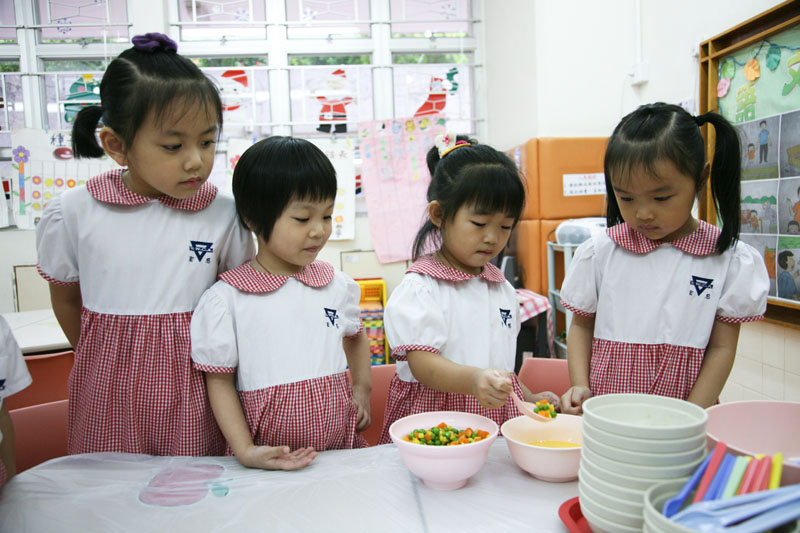 Children are mixing the green peas and corns into the eggs