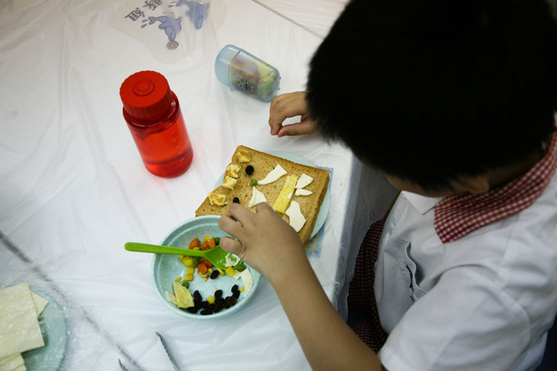 學童用食物裝飾麵包,製成麵包臉譜