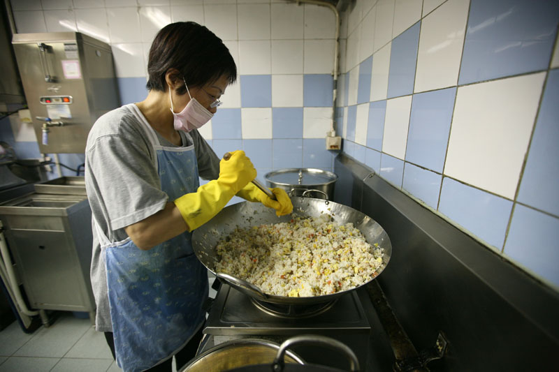 A staff member is cooking lunch for children
